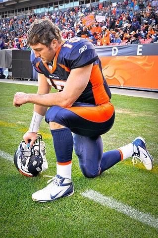 Tim Tebow kneeling in prayer before a game
