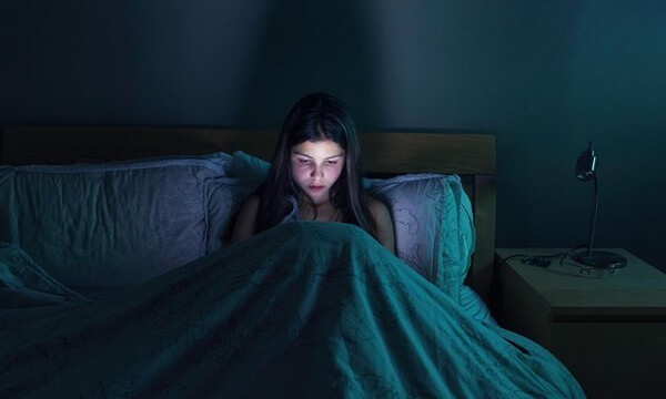 A teenage girl vamping on her phone through the night